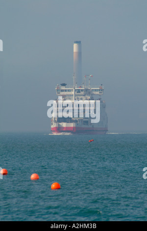 Ferry Red Funnel Osprey rouge émerge d'un banc de brouillard dans le soleil du printemps avec cheminée centrale de Fawley en arrière-plan Banque D'Images