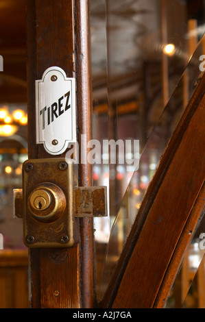 Détail d'une porte avec une serrure en laiton émail un panneau disant tirez (tirer) et une fenêtre en verre à facettes Le Bistrot du Peintre est un ancien café de Paris cafe bar restaurant de style art nouveau avec du cuivre poli, miroirs et signes vieux Banque D'Images