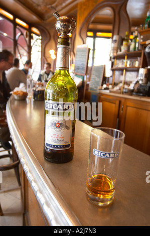 Une bouteille de Ricard et pastis 45 un verre sur le zinc d'un bar dans un bar-café à Paris. Dans l'arrière-plan des gens assis au bar et b Banque D'Images