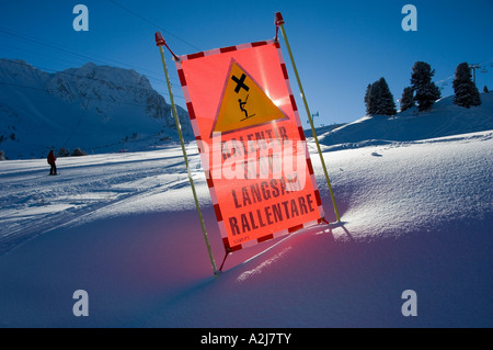 Inscrivez-lent pour les skieurs traversant une voie de remorquage de ski dans les alpes Banque D'Images