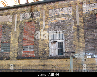 Mur de brique à l'aide de dispositifs de réparation et le cadre de la fenêtre fermée avec windows à l'aide de briques de couleurs différentes Banque D'Images