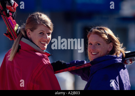 Deux skieurs femme regarde en arrière sur leurs épaules comme ils portent leurs skis et la tête pour les pistes Banque D'Images