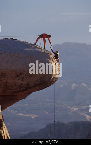 Grimpeur mâle sur une élingue de sécurité s'adresse à une femme comme elle l'alpiniste se dirige vers le haut et sur un affleurement de roche au sommet Banque D'Images