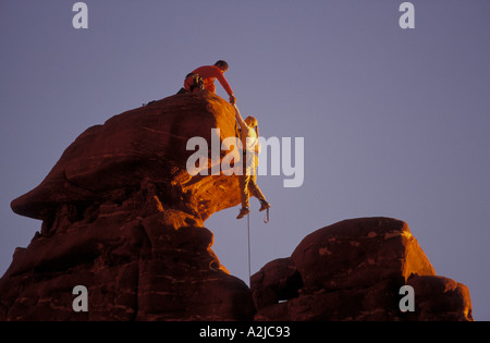 Grimpeur de sexe masculin s'adresse à une femme comme elle l'alpiniste se dirige vers le haut et sur un affleurement de roche au sommet Banque D'Images