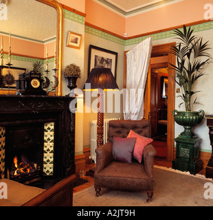 Fauteuil et lampe allumée à côté de la cheminée de marbre noir en rose et vert 80 salon avec rideau sur porte Banque D'Images