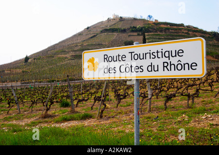 Un panneau routier indiquant la route touristique des Côtes du Rhône, les routes touristiques dans le RDC, à l'arrière-plan l'Hermitage Hill avec la Maison Blanche maison et vignoble. L'Ermitage vignes sur la colline derrière la ville de Tain-l'Hermitage, sur la colline en pente raide, en terrasses en pierre. Parfois orthographié Ermitage. Tain l'Hermitage, Drôme, Drôme, France, Europe Banque D'Images