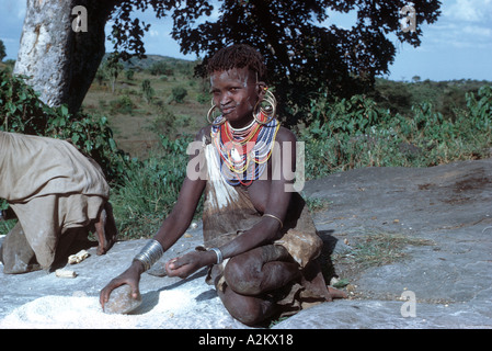 Jeune femme Pokot Ouest Maïs Broyage sur affleurement rocheux Morun River dans le nord du Kenya Banque D'Images