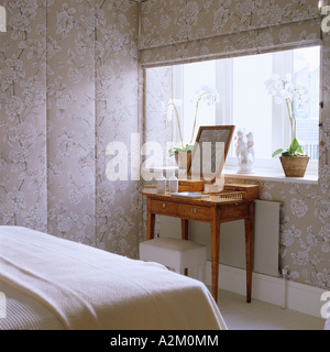 Coiffeuse dans la chambre avec du papier peint à motifs floraux et des stores Banque D'Images