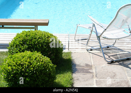 Banc vide et d'une chaise longue au bord de la piscine Banque D'Images