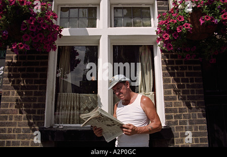 UK ANGLETERRE LONDRES Man reading newspaper hors pub sur fringe de Columbia Road Flower Market. Dimanche midi. L'été Banque D'Images