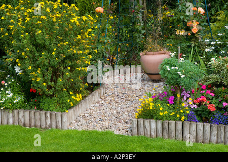 Chemin de galets et lit de fleur bordée de poteaux de bois Banque D'Images