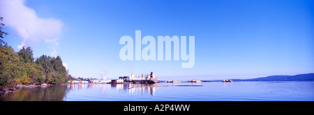 Crofton, île de Vancouver, BC, en Colombie-Britannique, Canada - Freighter et les copeaux de bois chargé de barges accostèrent à Pulp & Paper Mill Village Banque D'Images