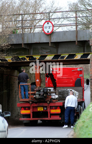 Un camion coincé sous un pont sur une route de campagne dans le Hampshire Banque D'Images