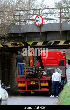 Un camion coincé sous un pont sur une route de campagne dans le Hampshire Banque D'Images