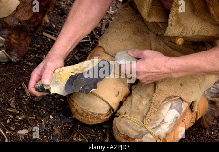 L'homme préhistorique Stoneage professionnel reenactors knapping flint au Musée de la vie galloise Cardiff St Fagans Wales UK Banque D'Images