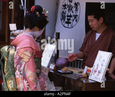 Fille en costume Geisha maiko stagiaire à la food à Kyoto Gion en kimono portant perruque maquillage lipst obi parasol Banque D'Images