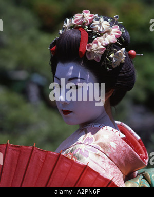 Fille de Geisha maiko stagiaire costume au jardin japonais de Kyoto Gion portant perruque obi kimono parasol makeup Banque D'Images