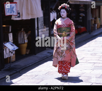 Fille de stagiaire costume Geisha maiko marche le long de la rue de Kyoto Gion portant perruque obi kimono parasol makeup Banque D'Images