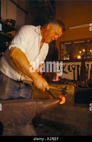 Rodney forgeron ouest travailler le métal chaud sur une enclume dans le village rural de shere à Surrey population d'environ 1000 Banque D'Images