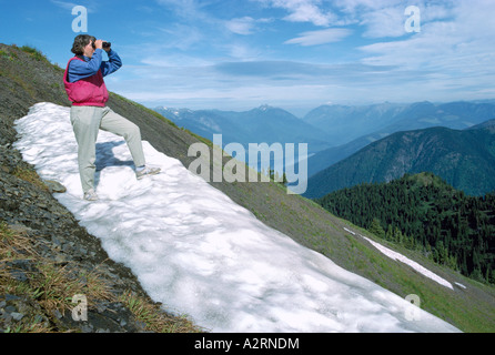 Femme regardant à travers des jumelles à Selkirk Mountains de l'Idaho Peak, BC, en Colombie-Britannique, Canada - Randonnées dans la région de Kootenay Banque D'Images