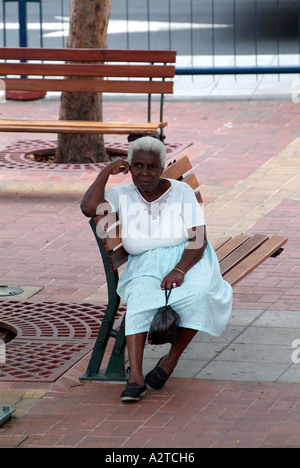 Vieille Femme noire assise sur un banc à Guayaquil, Équateur. Banque D'Images