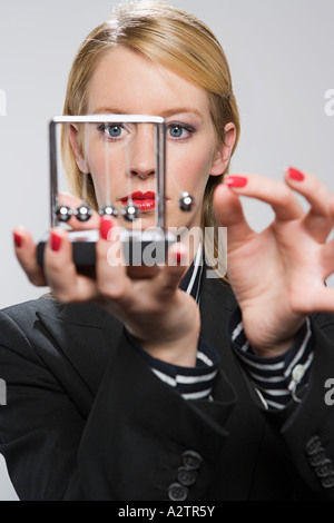 Businesswoman holding a newtons cradle Banque D'Images