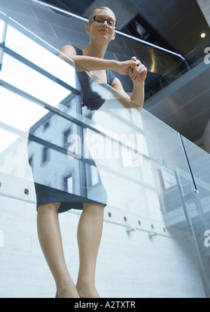 Businesswoman leaning against guard rail, low angle view Banque D'Images