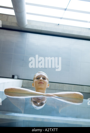 Femme appuyée contre le garde-corps en verre, low angle view Banque D'Images