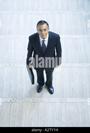 Businessman holding briefcase, portrait, high angle view Banque D'Images