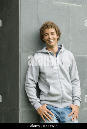 Jeune homme debout avec les pouces dans les poches, smiling at camera Banque D'Images