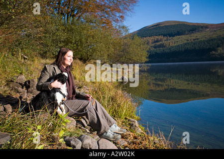 Femme assise avec chien dans l'automne, réservoir de Talybont, Brecon Beacons NP, FR Banque D'Images