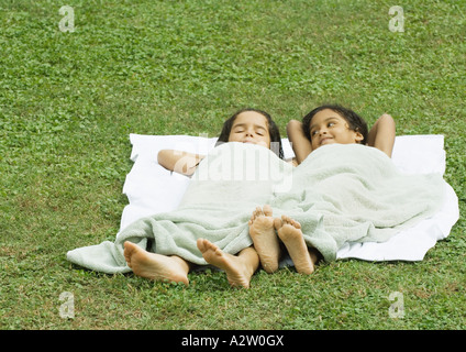 Deux jeunes filles se trouvant dans l'herbe, sur une serviette et couverts d'une serviette Banque D'Images