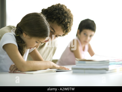 Aider un adolescent plus jeune soeur aux devoirs Banque D'Images