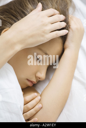 Girl sleeping in bed, caressant la main de mère head Banque D'Images