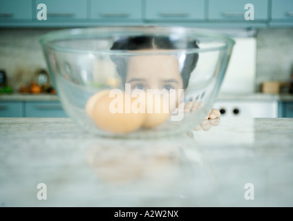 Girl looking through bol contenant des œufs Banque D'Images