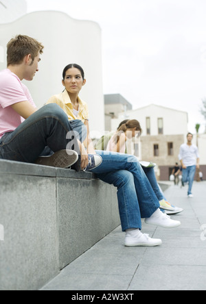 Adolescents assis à l'extérieur en zone urbaine Banque D'Images