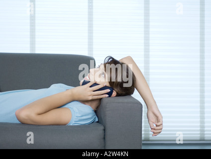 Femme allongée sur un canapé, parlant au téléphone Banque D'Images