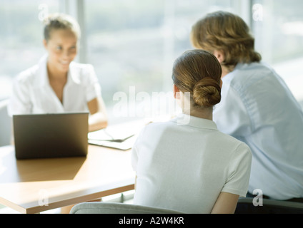 L'homme et de la femme assise en face de table smiling businesswoman, vue arrière Banque D'Images