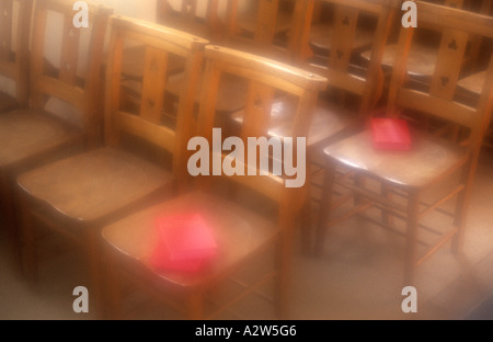 Atmospheric rangées de chaises en bois simple avec quelques livres rouges se trouvant sur place baignée de soleil d'or Banque D'Images