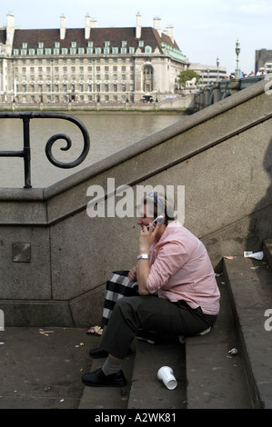 Woman in pink shirt assis sur les escaliers de Westminster Bridge en utilisant son téléphone portable Banque D'Images