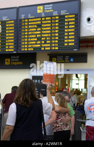 Guide féminin espagnol attend devant le terminal des arrivées message board avec liste des passagers du Reina Sofia sur TFS Banque D'Images