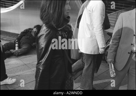 Les piétons passer devant un sans-abri dormant sur le trottoir devant une banque, Shinjuku, Tokyo, Japon, Asie Banque D'Images