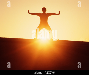 Silhouette d'un homme debout sur une crête au lever du soleil. Arts martiaux Kung Fu. Banque D'Images