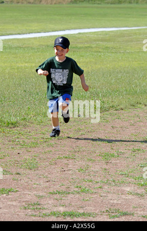 Pre-K Enfant tournant autour d'un terrain de baseball dans un pré-K T-Ball jeu pratique Banque D'Images