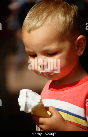 Petit garçon à l'extérieur manger une glace à cône. Banque D'Images