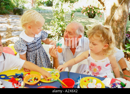 Le goûter des enfants à l'extérieur dans le jardin avec grand-père. Banque D'Images