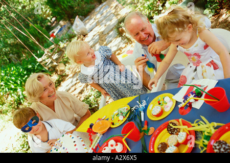 Le goûter des enfants à l'extérieur dans le jardin avec grand-mère et grand-père. Banque D'Images