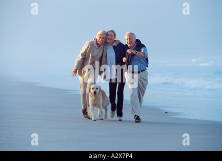 La marche de la famille plus âgés leur Labrador chien sur la plage. Banque D'Images