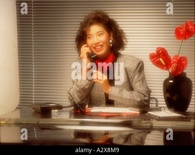 Femme d'affaires assise au bureau en utilisant le téléphone. Banque D'Images