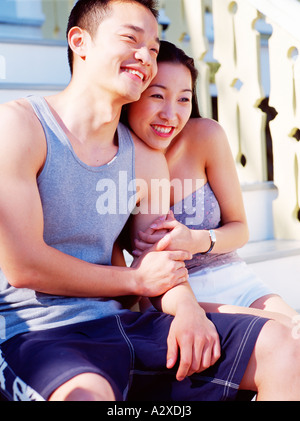 Young couple outdoors sitting on steps à la plage. Banque D'Images